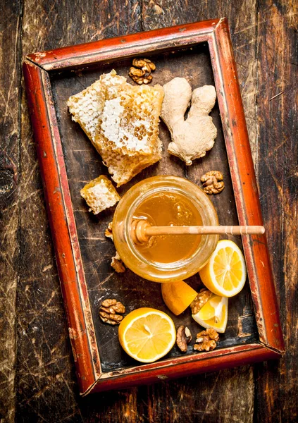 Honey background . Fresh honey with lemon and ginger in an old tray.