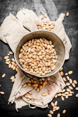 Kumaş üzerine eski bir kova içinde fıstık.