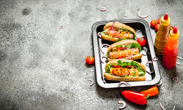 Street food. hot dogs with herbs and vegetables in the pan.On rustic background.