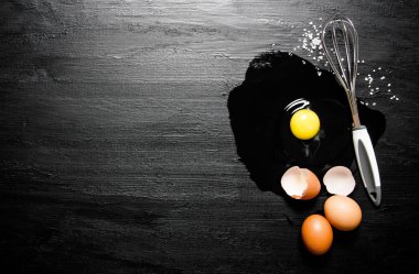 Kırık yumurta çırpma teli ile. Siyah ahşap arka plan üzerine.
