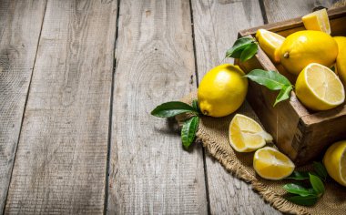 Kumaş üzerine bir kutu içinde yapraklarla limon . 