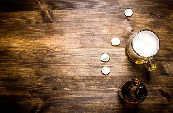 Beer style - bottle, beer in the glass and covers on wooden table. Free space for text. — Stock Photo, Image