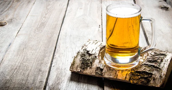 Kieliszek lekkie piwo na stoisku brzoza. Na drewnianym stołem. — Zdjęcie stockowe