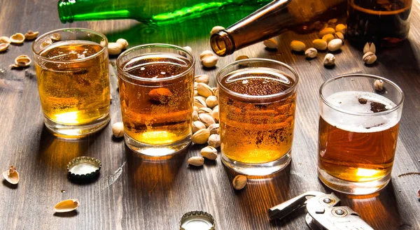 Quatro cervejas com pistache em uma mesa de madeira . — Fotografia de Stock