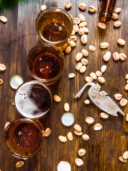 Quattro birre con pistacchi su un tavolo di legno . — Foto Stock