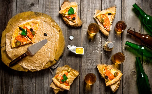 Pizza y cerveza para cuatro personas. Sobre una mesa de madera . — Foto de Stock