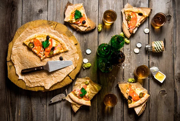 Pizza y cerveza para cuatro personas. Sobre una mesa de madera . — Foto de Stock