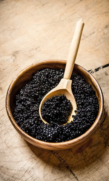 Caviar negro en un tazón con una cuchara de madera . — Foto de Stock