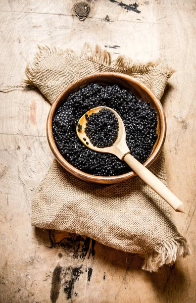 Caviar negro en cuenco de madera sobre tela vieja. Sobre mesa de madera . — Foto de Stock