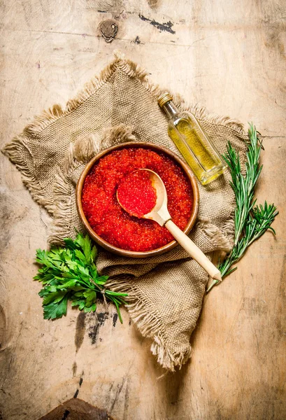 Red caviar in a bowl with herbs and oil for an old fabric. — Stock Photo, Image
