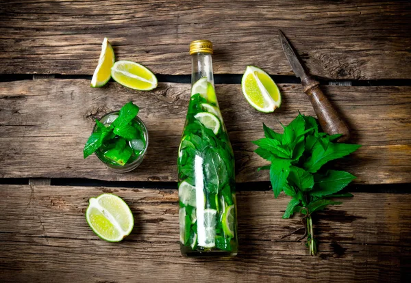 Gli ingredienti per il cocktail - lime, menta, coltello, viene preparato anche cocktail in bottiglia e nel bicchiere . — Foto Stock