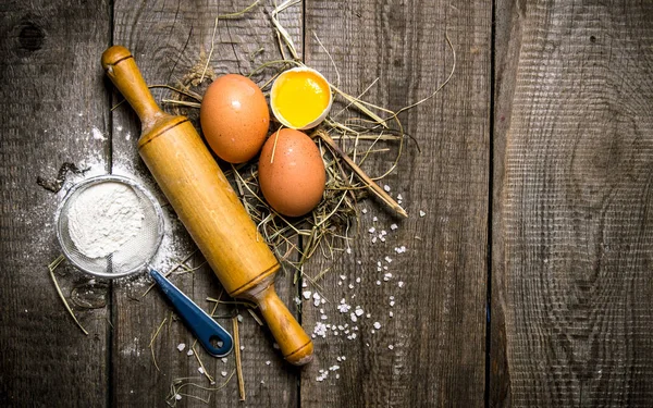 Preparación de la masa. Ingredientes para la masa huevos con harina y con un rodillo . — Foto de Stock