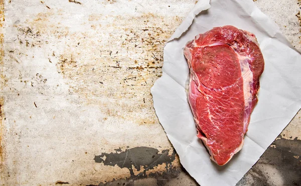 Un trozo grande de carne fresca cruda sobre papel . — Foto de Stock