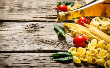 Mixed dry pasta and spaghetti, with tomatoes, herbs and olive oil.  clipart