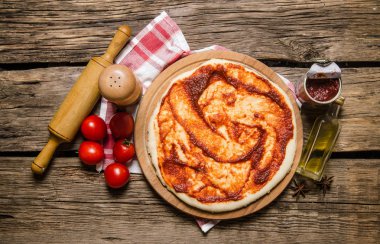 Haddelenmiş dışarı pizza hamuru oklava kumaş ile domates sosu ile. 