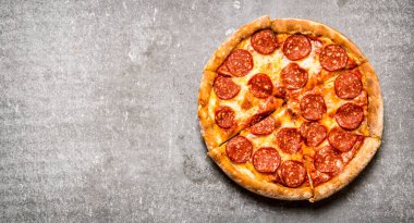 Pepperoni pizza üstten görünüm. Taş masanın üzerine .