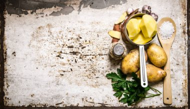 Rustik zemin üzerine tencerede soyulmuş patates kavramı. Metin için boş alan.