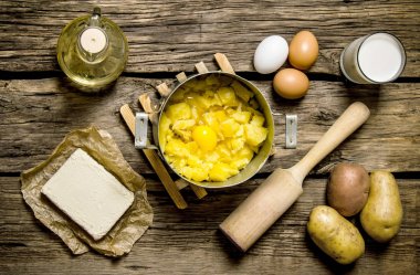 Ingredients for mashed potatoes - eggs, milk, butter and potatoes on wooden background. clipart