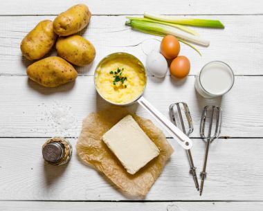Patates püresi malzemeler pişirme: patates, süt, yumurta, tereyağı ve diğer beyaz bir ahşap tablo.