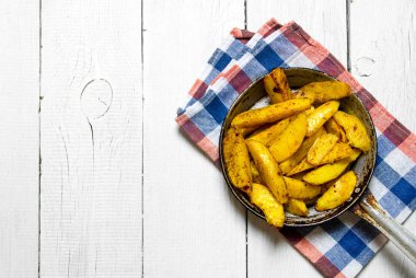 Beyaz ahşap bir masa üzerinde bir tavada fırında patates. Metin için boş alan.