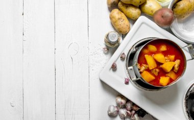 Et ve Beyaz ahşap masa üzerinde bir elektrikli Ocak içinde baharatlar ile haşlanmış patates. Metin için boş alan.