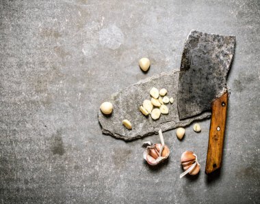 Kıyılmış taze sarımsak ve taş bir stand eski balta. 