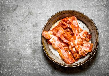 Bir tavada kızarmış domuz pastırması. Taş zemin üzerine.