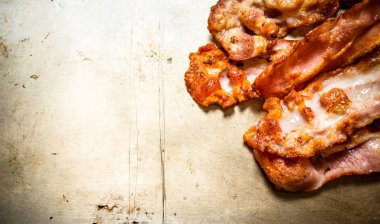 Kızarmış domuz pastırması. Eski rustik arka plan üzerinde.