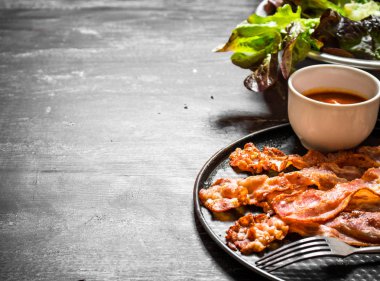 Kızarmış domuz pastırması sos ve yeşillik ile.