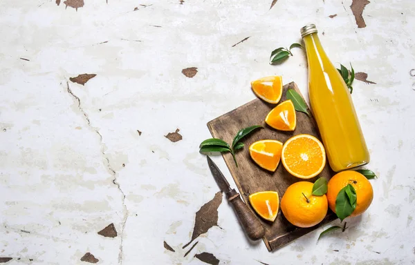 Fresh orange juice with oranges, leaves and a knife.