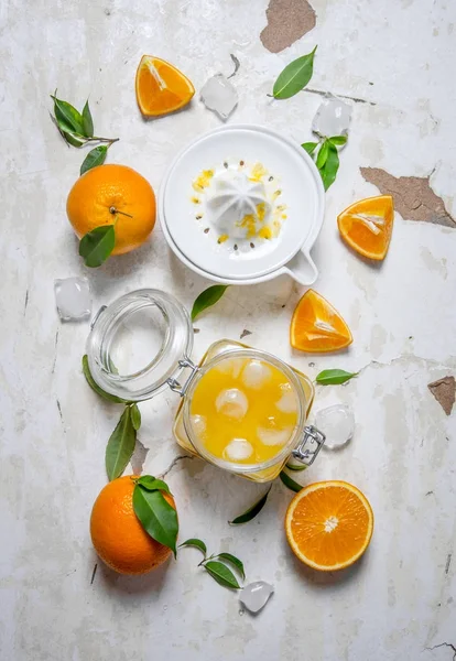 Sumo de laranja fresco com gelo, com fatias de laranjas e um espremedor . — Fotografia de Stock