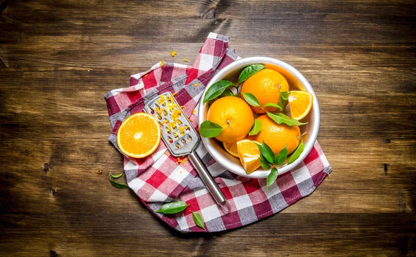 Cup with fresh oranges, zest and grater on fabric.