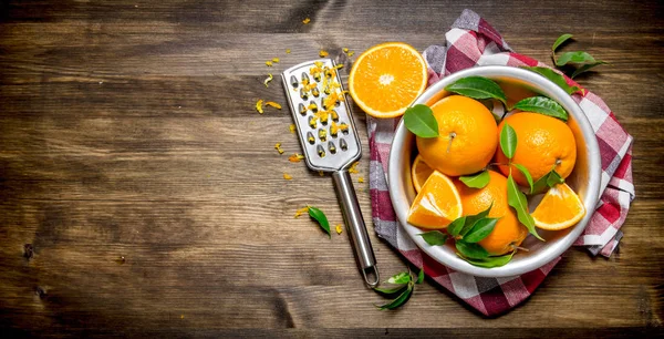 Cup with fresh oranges, zest and grater on fabric.