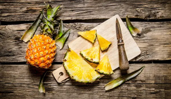 Gesneden verse ananas met een mes op een snijplank. — Stockfoto