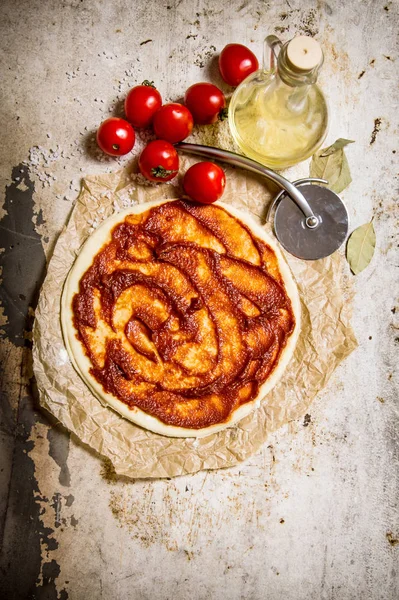 A massa de farinha de pizza estendida com tomates, pasta de tomate e óleo de azeitona . — Fotografia de Stock