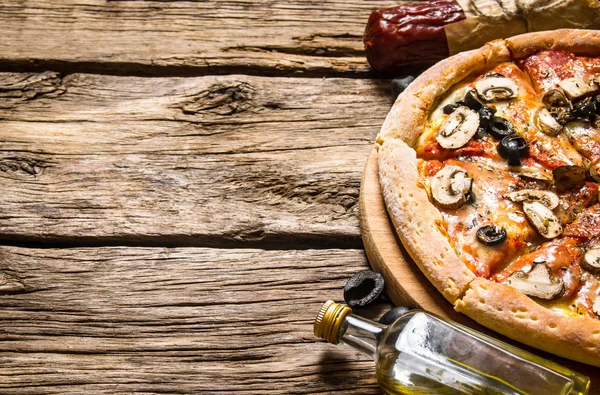 Italian pizza and different ingredients - meat, mushrooms, tomatoes and olive oil.