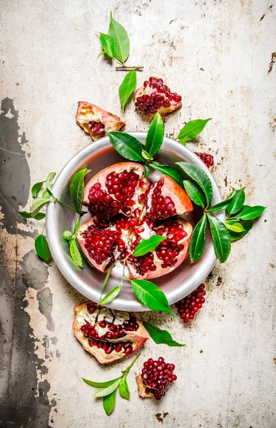 Stücke Granatapfel mit Blättern in einer Tasse Draufsicht. — Stockfoto