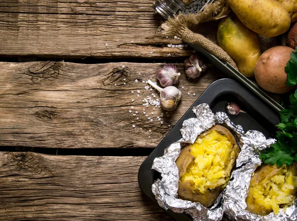 Fırında patates tuz ve sarımsak ahşap bir masa ile folyo. Metin için boş alan.