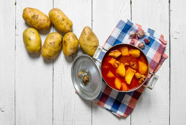 Batatas cozidas com carne e especiarias em fundo de madeira branca  . — Fotografia de Stock