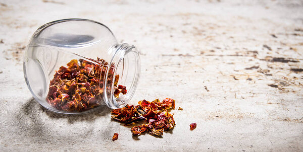 Dried red Chili peppers in the jar. On rustic background.