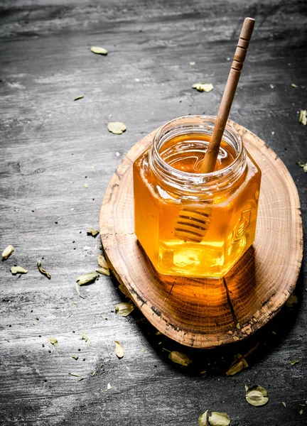 Pot en verre miel avec cuillère sur un coffre en bois . — Photo