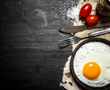 Sahanda yumurta domates ve tuz. Siyah ahşap arka plan üzerine.