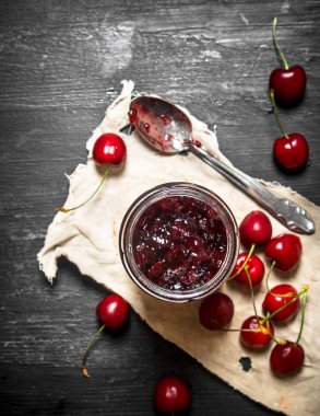 Eski kumaş üzerine bir kavanoza kiraz reçeli.