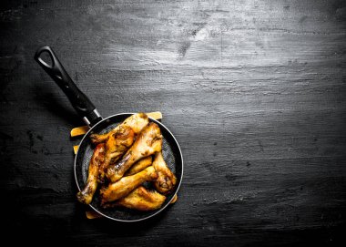 Bir tavada kızarmış tavuk budu.