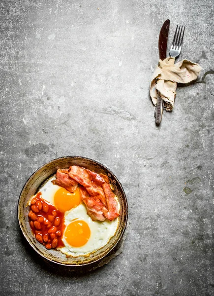 Yumurta ve fasulye tavada kızarmış domuz pastırması.