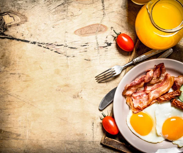 Orange juice with fried eggs, bacon, and slices of bread. — Stock Photo, Image