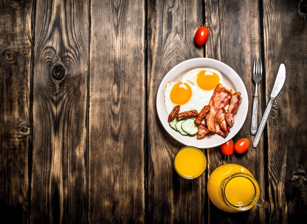 Fried bacon with eggs and orange juice. — Stock Photo, Image