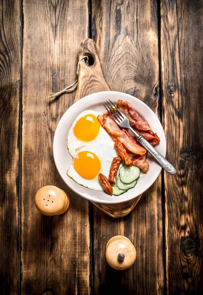 tabak kızarmış yumurta, pastırma, salatalık ve tütsülenmiş sosis.