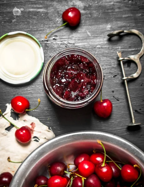 Mermelada de cereza y herramienta de metal para cerezas . — Foto de Stock