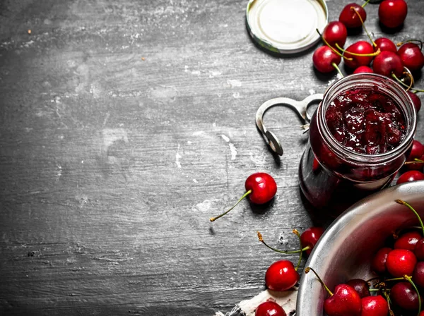 Cherry jam and metal tool for cherries. — Stock Photo, Image